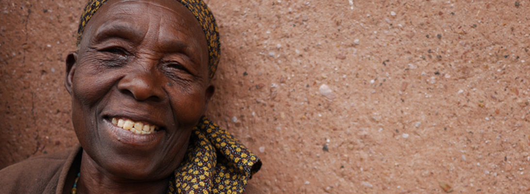 older african woman against a mud wall